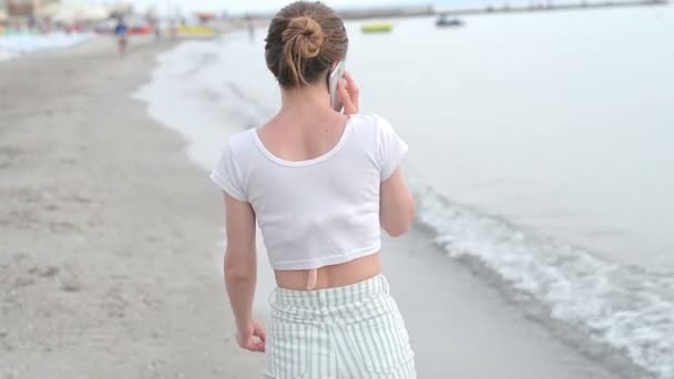 Jonge vrouw met mobiele telefoon op een strand — Stockvideo