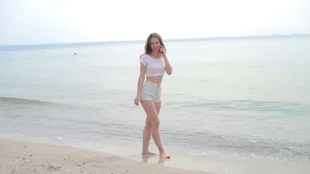 Jeune femme avec téléphone portable sur une plage — Video