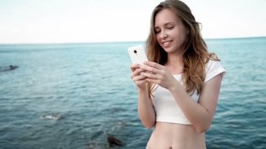 Holding ve gün batımı Hawaii plajda akıllı telefon bakarak karışık yarış oldukça gülümseyen genç kadın