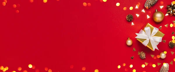 Mutlu Noeller ve sol tarafında telif alanı olan mutlu tatiller arkaplan kartı. Noel hediyeleri, ışıklar bokeh ve kırmızı arka plan manzaralı altın dekor. Kış Xmas bayramı teması düz yatar