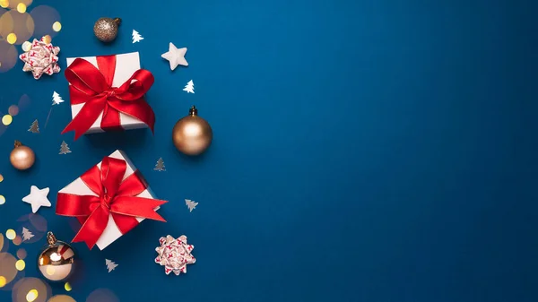Mutlu Noeller ve mutlu bayramlar tebrik kartı geçmişi ve telif alanı sağ tarafta. Mavi arka planda Noel hediyeleri ve altın dekor. Düz yatış tarzında kış xmas tatil teması