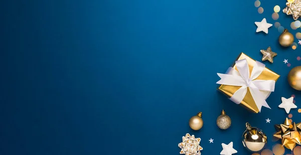 Mutlu Noeller ve mutlu bayramlar tebrik kartı arkaplanı sol tarafta. Altın Noel hediyeleri ve mavi arka plan manzaralı dekor. Düz yatış tarzında kış xmas tatil teması