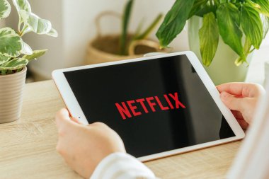 VALENCIA, İspanya - Ekim 2020: Netflix uygulaması bir tablet ekranda. Genç Kız, Talep üzerine TV programları, Belgesel, Seriler ve Filmler 'i oturma odasında tablet ile izliyor.