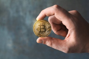 Altın bir bitcoin gösteren bir adamın yakın çekimi. Dijital merkeziyetçilikten arındırılmış finans kavramında BTC ve kripto para birimi işi