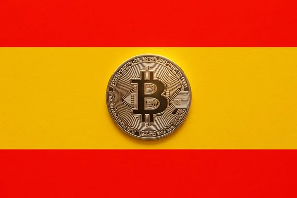 One bitcoin on a Spanish flag background. New regulations and laws for cryptocurrencies enters into force in Spain