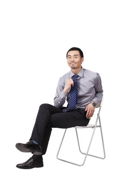 Um jovem homem de negócios alegre sentado postura — Fotografia de Stock