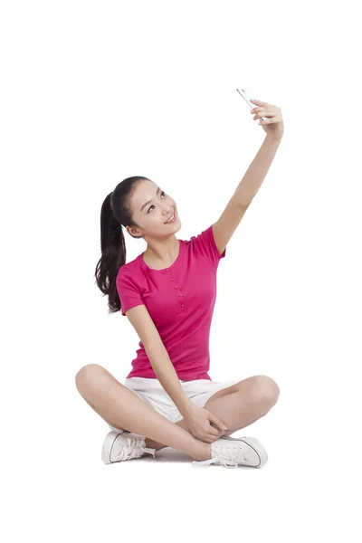 Young woman photographing herself with mobile phone — Stock Photo, Image