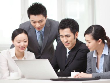 Bir grup iş adamı bilgisayarla çalışmayı tartışıyor