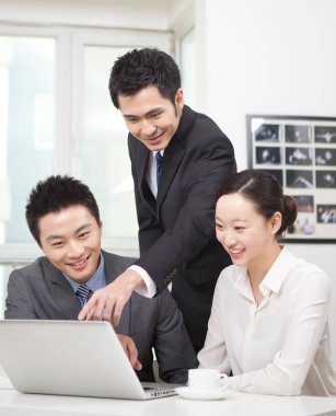 Bir grup iş adamı bilgisayarla çalışmayı tartışıyor