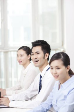 Bir grup iş adamı konferans masasında oturuyor. 