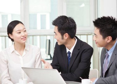 Bir grup iş adamı bilgisayarla çalışmayı tartışıyor