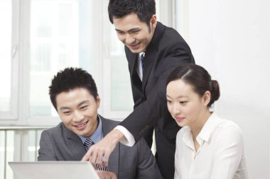 Bir grup iş adamı bilgisayarla çalışmayı tartışıyor