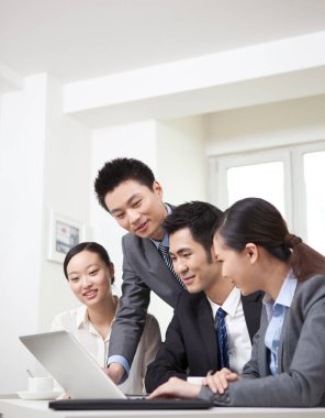 Bir grup iş adamı bilgisayarla çalışmayı tartışıyor