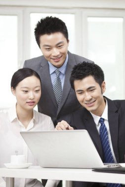 Bir grup iş adamı bilgisayarla çalışmayı tartışıyor