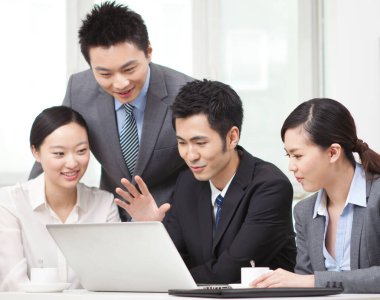 Bir grup iş adamı bilgisayarla çalışmayı tartışıyor