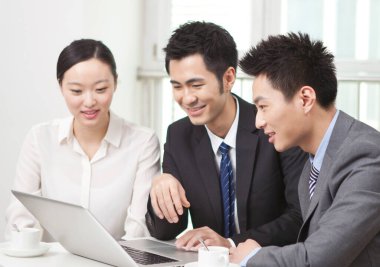 Bir grup iş adamı bilgisayarla çalışmayı tartışıyor