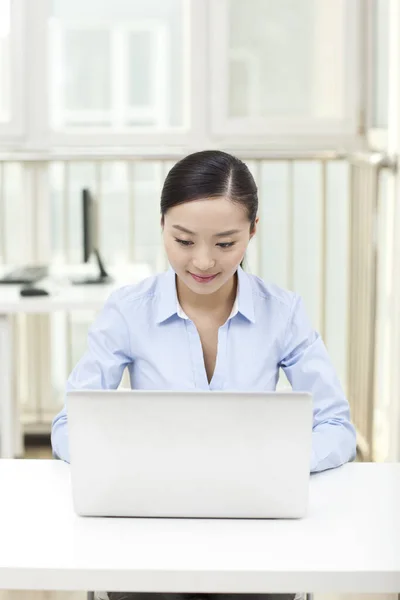 Uma jovem mulher usando laptop no escritório — Fotografia de Stock