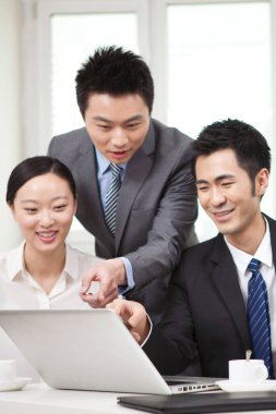 Bir grup iş adamı bilgisayarla çalışmayı tartışıyor