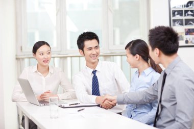 Genç iş adamları ofiste el sıkışıyor. 