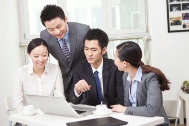 Bir grup iş adamı bilgisayarla çalışmayı tartışıyor