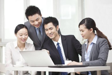 Bir grup iş adamı bilgisayarla çalışmayı tartışıyor