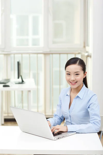 Una giovane donna che utilizza il computer portatile in ufficio — Foto Stock