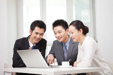 Bir grup iş adamı bilgisayarla çalışmayı tartışıyor