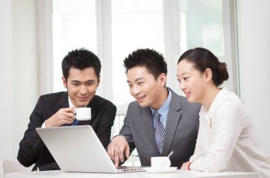 Bir grup iş adamı bilgisayarla çalışmayı tartışıyor