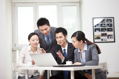 Bir grup iş adamı bilgisayarla çalışmayı tartışıyor