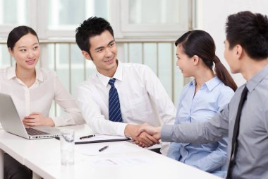 Genç iş adamları ofiste el sıkışıyor. 