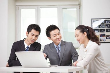 Bir grup iş adamı bilgisayarla çalışmayı tartışıyor