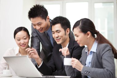 Bir grup iş adamı bilgisayarla çalışmayı tartışıyor