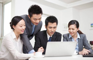Bir grup iş adamı bilgisayarla çalışmayı tartışıyor