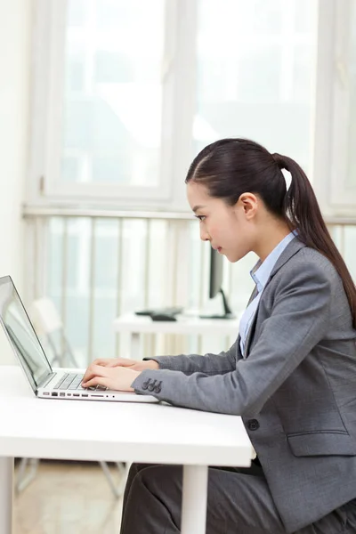 Uma jovem mulher usando laptop no escritório — Fotografia de Stock