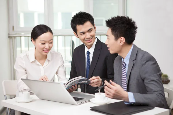 Group of businesspeople discussing with a magazine in office — Stock Photo, Image