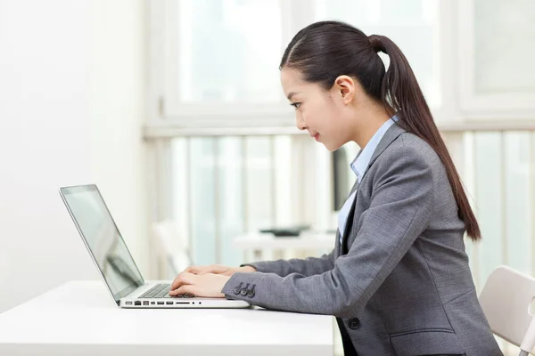 Uma jovem mulher usando laptop no escritório — Fotografia de Stock