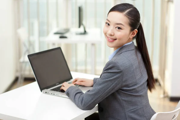 Uma jovem mulher usando laptop no escritório — Fotografia de Stock