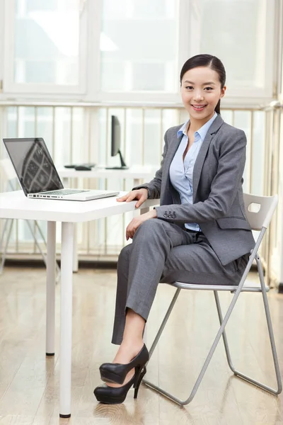 Jovem mulher sentada na frente do laptop — Fotografia de Stock