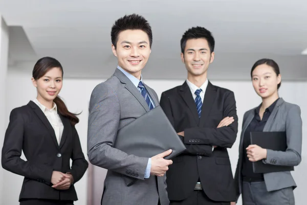 Quatre jeunes employés de bureau les mains croisées à l'intérieur, portrait — Photo