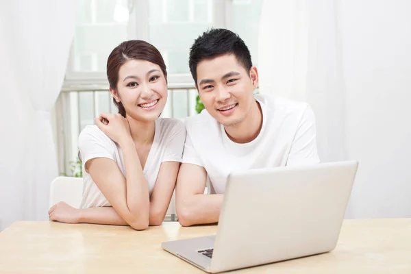 Um jovem casal usando laptop em casa — Fotografia de Stock
