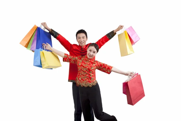 Porträt eines jungen Paares in Tang-Anzügen, das Einkaufstüten hochhält — Stockfoto