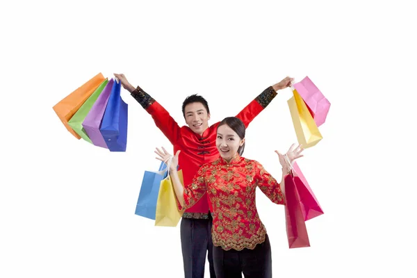 Porträt eines jungen Paares in Tang-Anzügen, das Einkaufstüten hochhält — Stockfoto