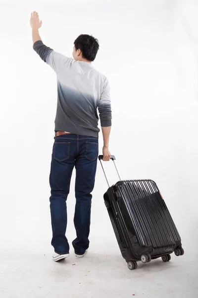 Portrait of young bisiness man pulling valise — Stockfoto