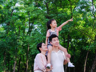 Üç kişilik mutlu bir aile parkta oynuyor.