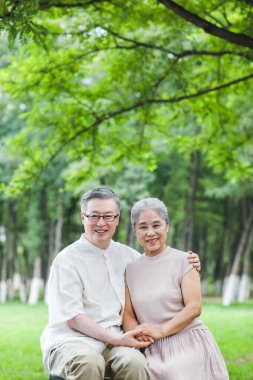 Parktaki sandalyelerde oturan mutlu yaşlı çift