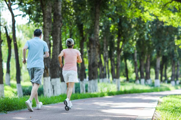 Pareja de ancianos corriendo en el parque al aire libre — Foto de Stock
