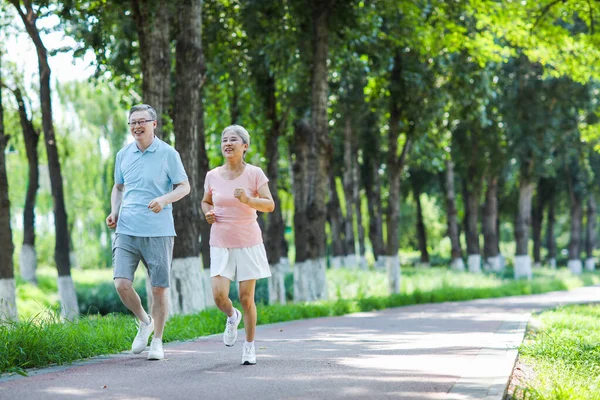 Pareja de ancianos corriendo en el parque al aire libre — Foto de Stock