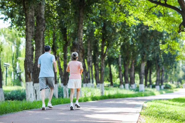 Pareja de ancianos corriendo en el parque al aire libre — Foto de Stock