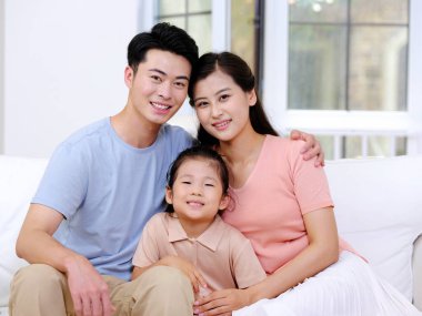 Üç kişilik mutlu bir aile oturma odasındaki kanepede oturuyor.