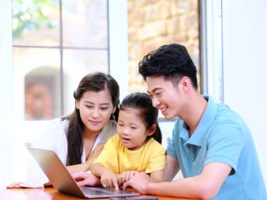 Üç kişilik mutlu aile dizüstü bilgisayar kullanıyor.